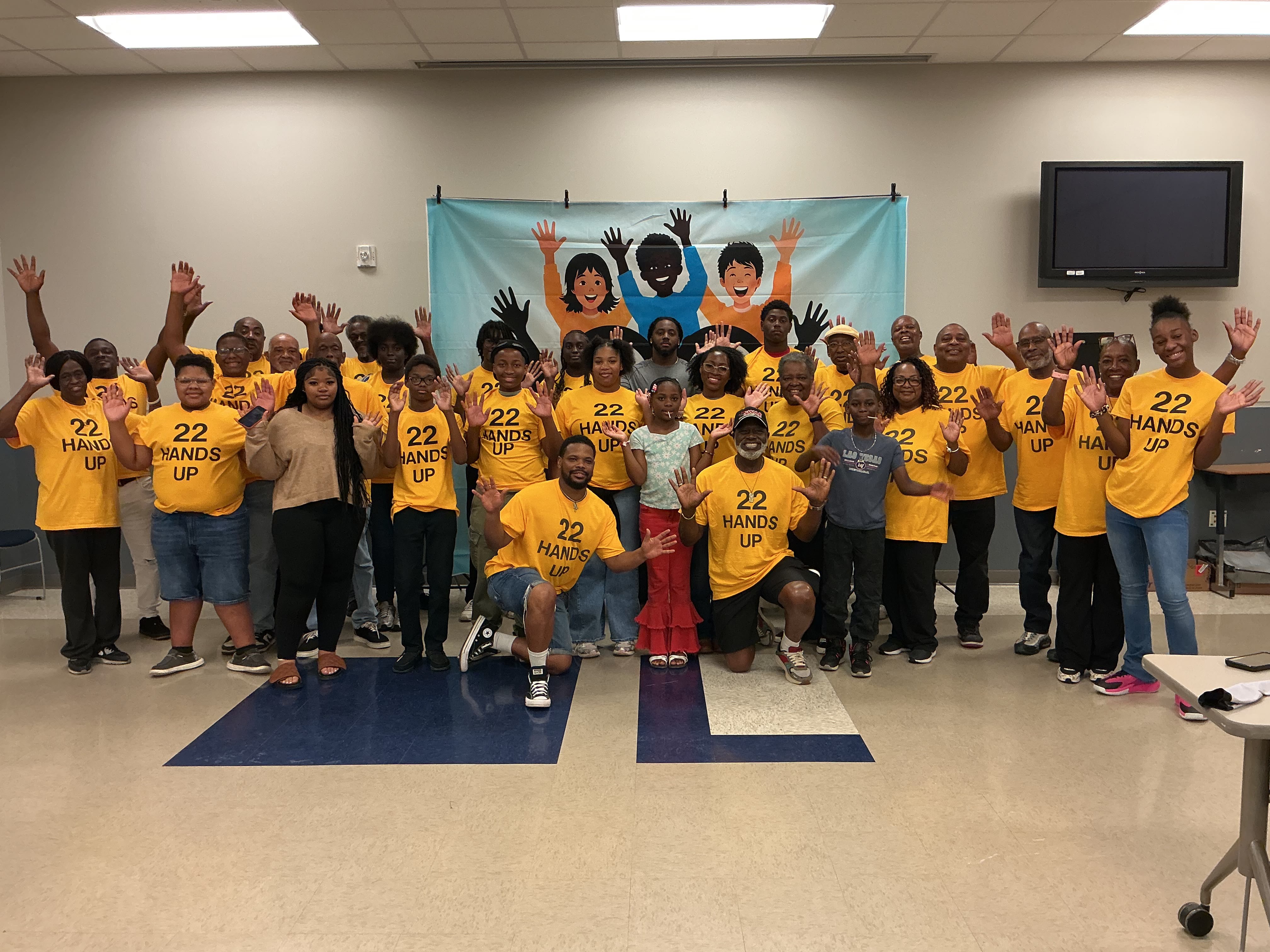 The 22 Hands Up group with hands raised in front of the banner