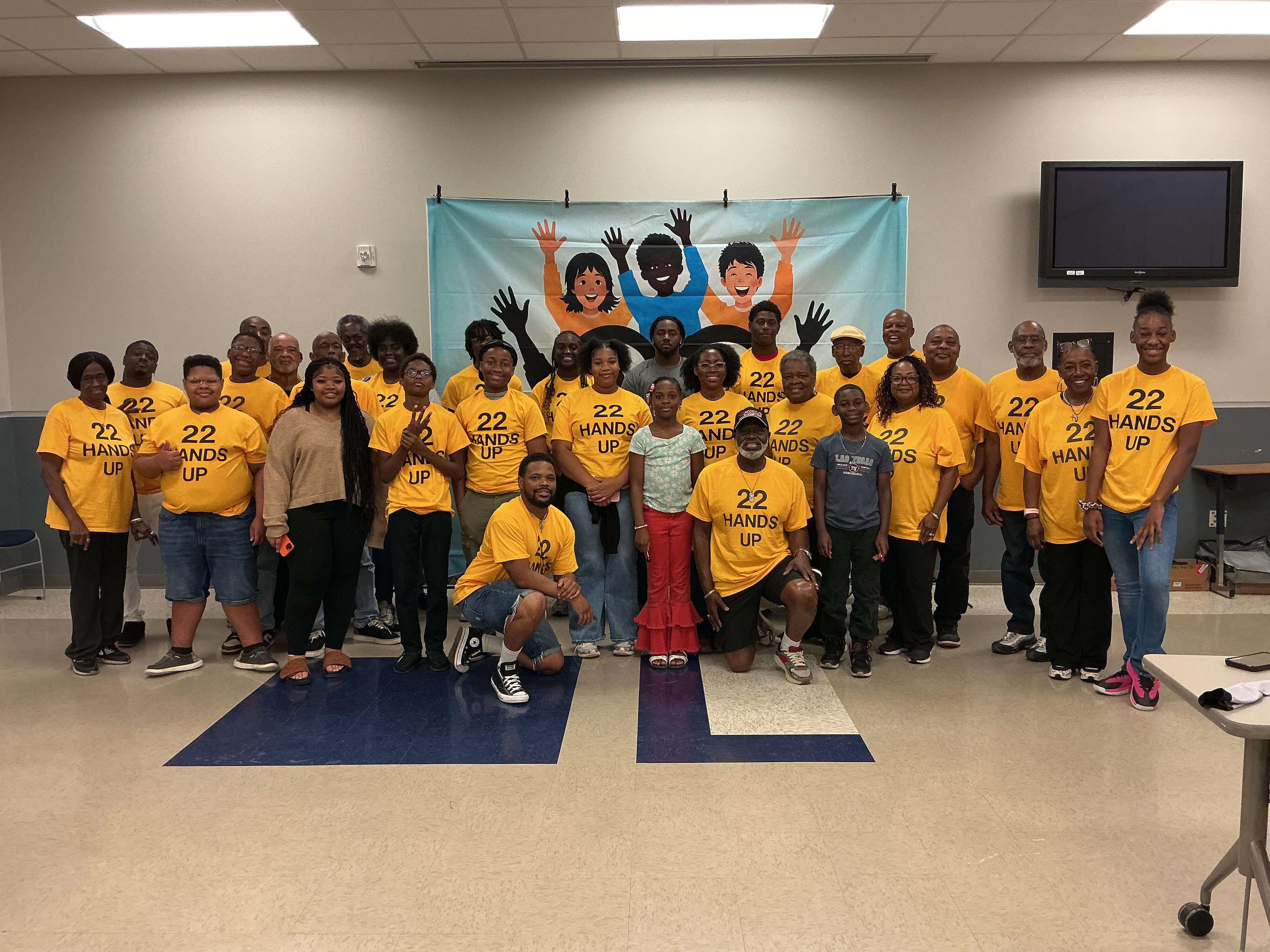 The full 22 Hands Up group of youth and mentors in yellow shirts at the etiquette workshop